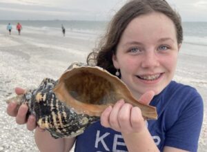 Smiling girl with a giant Florida horse conch shell on our Marco Island shelling tour