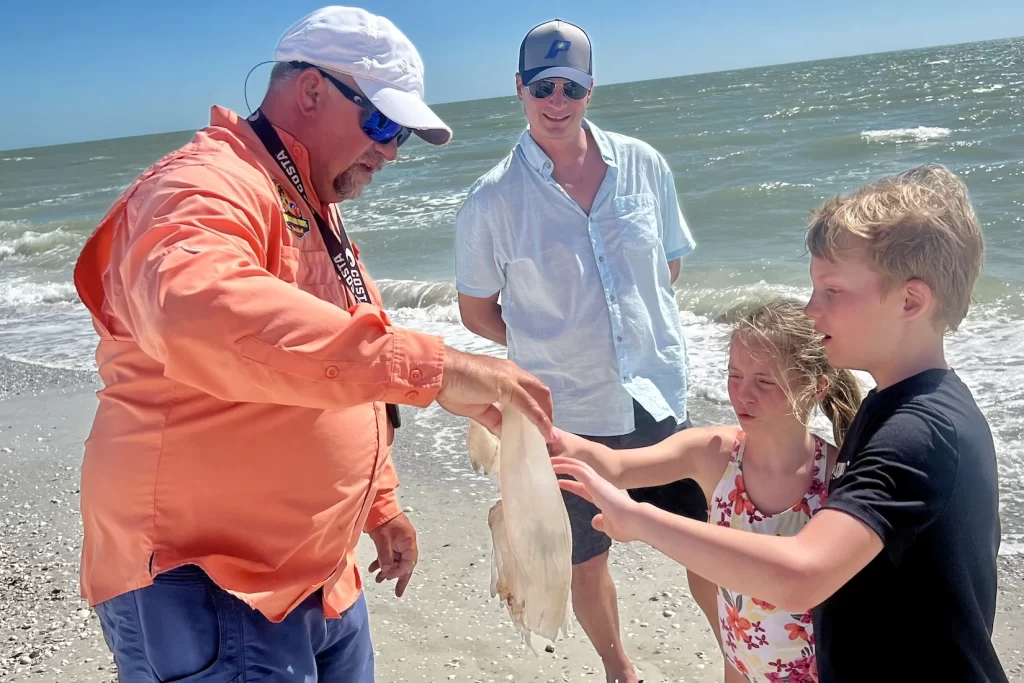 Captain and Florida certified master naturalist eco-tour guide showing some kids a moon jellyfish