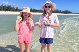 Two kids with sand dollars on a remote sand bar